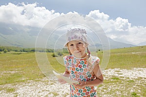 Little girl with melon slice in hand enjoying being on Alpine meadow
