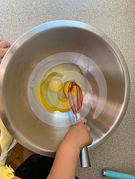 Little Girl Mixing Eggs While Baking with Parents