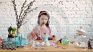 Little girl and mom paints eggs for Easter. Child of European appearance , decor on the table. Happy family makes