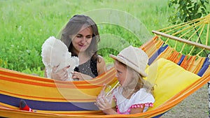 Little Girl with Mom Playing with Toy in Hammock