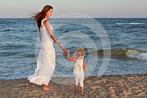 Little girl with mom walk along the seashore