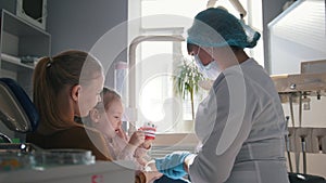 Little girl with mommy in dentist room - doctor examines the girl`s teeth