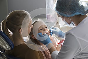 Little girl with mommy in dentist room - doctor examines the girl`s teeth