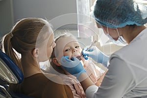 Little girl with mommy in dentist room - doctor examines the girl`s teeth