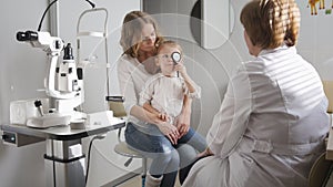 Little girl with mommy in ophthalmology - optometrist checking little child`s vision