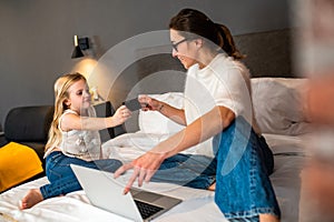 Little girl with mother doing shopping online using credit card and laptop for internet payment