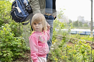 Little girl with mother going to railway station at spring time. Serious toddler looking at camera