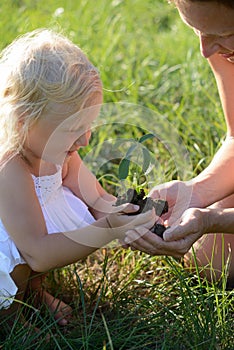 Little girl and mother holding a plant