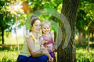 Little girl with mother look a yellow flower on the green background