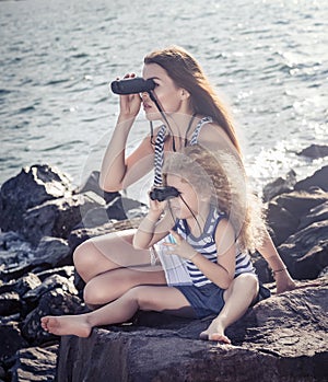 Little girl and mother looking far away with binoculars