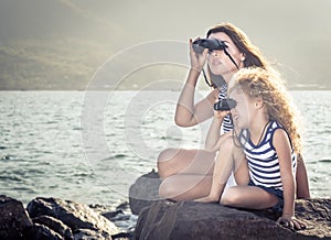 Little girl and mother looking far away with binoculars