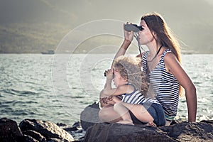 Little girl and mother looking far away with binoculars