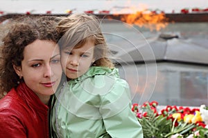 Little girl and mother stands near memorial