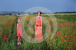 Little girl with mother walking on the poppy field