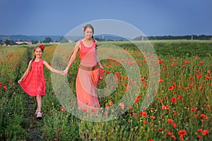 Little girl with mother walking on the poppy field