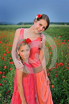 Little girl with mother walking on the poppy field