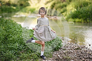 Little girl in nature stream wearing beautiful dress