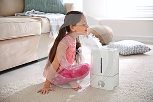 Little girl near air humidifier at home