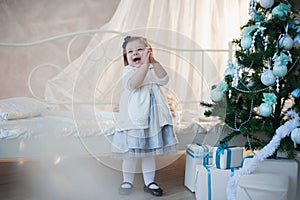 Little girl near Christmas tree with presents rejoices holiday, new year, decorations, gift, box, holiday, lifestyle