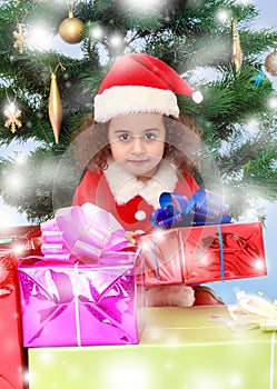 Little girl near the Christmas tree surrounded by gifts