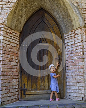 Little girl near the old fashioned door of the church