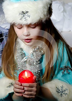 Little girl in a New Year costume with a candle.