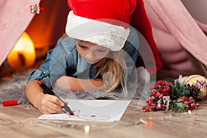 A little girl on New Years Eve writes a letter to Santa Claus. Christmas wishes, home holiday