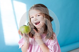 Little girl with no teeth eats fruit apple