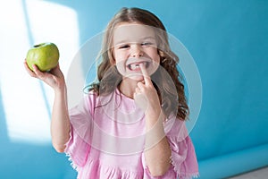 Little girl with no teeth eats fruit apple