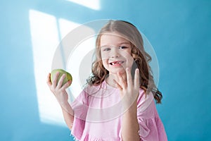 Little girl with no teeth eats fruit apple