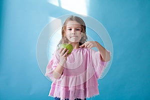 Little girl with no teeth eats fruit apple