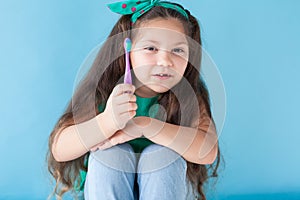 Little girl with no teeth with a toothbrush in dentistry