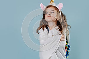 Little girl in noble stance wearing unicorn headband, wrapped in bed cover