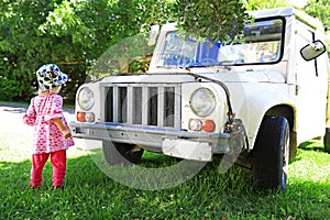 Little girl and old white jeep, child is in front of the car