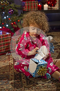 Little girl opening Christmas gift, vertical