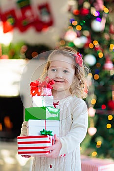 Little girl opening Christmas presents at fire place