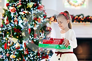 Little girl opening Christmas presents at fire place