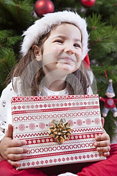 Little girl opening he present under Christmas tree