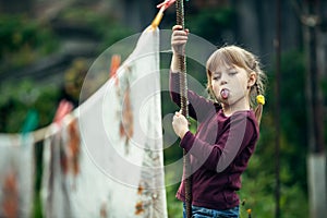 Little girl outdoor, looks into the camera and shows the language.