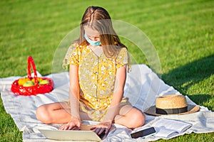 Little girl outdoors in the park with computer