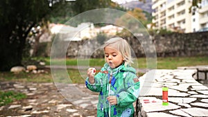 Little girl in overalls spitting while trying to blow soap bubbles