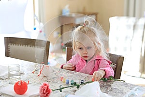 Little Girl is painting christmas ball at he kitchen counter