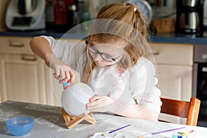 Little girl painting globe or ball with colors. School child making earth globe for school project. Happy kid with