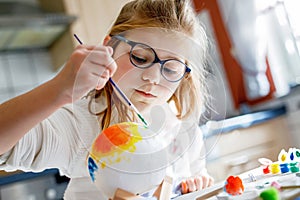 Little girl painting globe or ball with colors. School child making earth globe for school project. Happy kid with