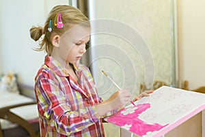 Little girl is painting a house for dolls