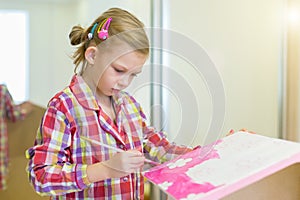Little girl is painting a house for dolls