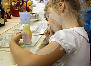 Little girl painting a matrioshka russian doll photo