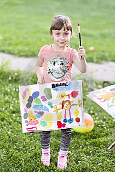 Little girl painting with paintbrush and colorful paints