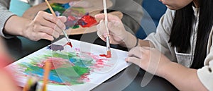 Little girl painting picture in art class with teacher.