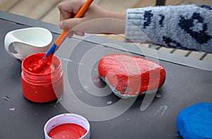 Little girl painting stone with red paint